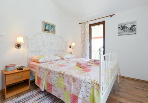 ein Schlafzimmer mit einem weißen Bett mit einer rosa und gelben Decke in der Unterkunft Holiday Home Marija-70m from beach in Vlašići