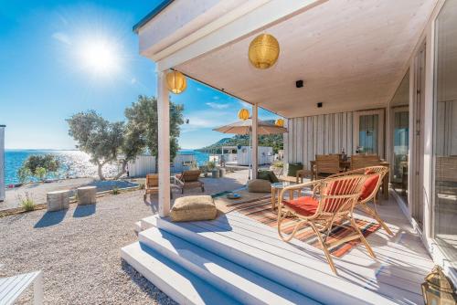 a porch of a house with chairs and an umbrella at BUQEZ Eco Resort - beachfront 20 & House 42 in Drage