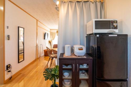 um micro-ondas em cima de um frigorífico numa sala de estar em ASAHI HOUSE 2nd floor - Vacation STAY 92921 em Naha