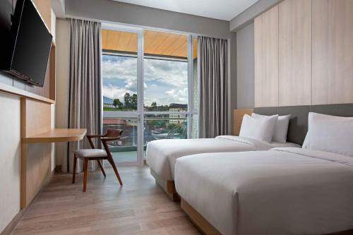 a hotel room with two beds and a window at Hotel Santika Bukittinggi in Bukittinggi