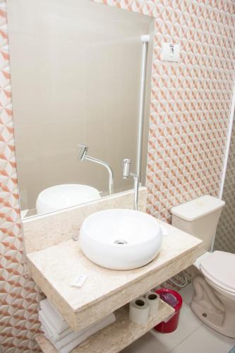 a bathroom with a sink and a toilet and a mirror at Hotel Morada do Mar in Guarujá