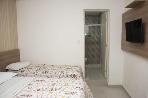 a small bedroom with a bed and a tv at Hotel Morada do Mar in Guarujá