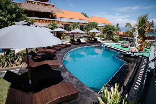 a swimming pool with chairs and an umbrella at Pandawa Resort & Spa Seaview in Nusa Penida