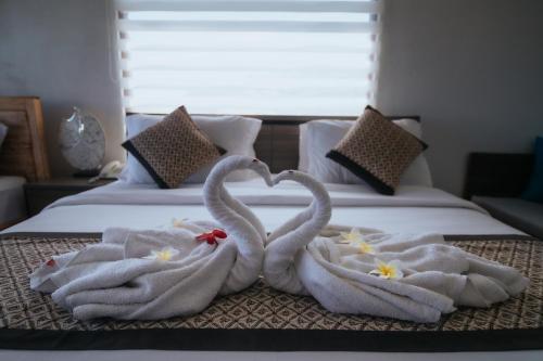 Dos cisnes están haciendo forma de corazón en una cama en Pandawa Resort & Spa Seaview, en Nusa Penida