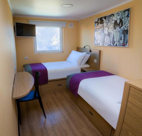 Habitación pequeña con 2 camas y mesa. en Hotel Modular Express Calama, en Calama
