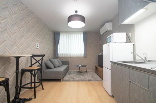 cocina y sala de estar con sofá y nevera en LA CHIC Stay Hakata Ⅱ, en Fukuoka