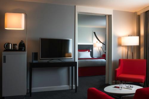 a living room filled with furniture and a tv at Mercure Paris CDG Airport & Convention in Roissy-en-France