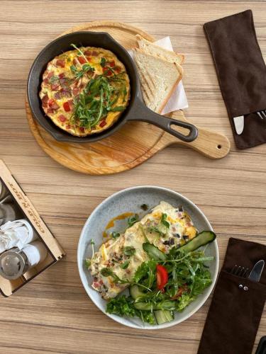 a table with a pan of pizza and a plate of salad at Eco Apart Hotel Astana in Astana