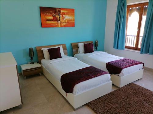 2 camas en una habitación con paredes azules en Le Sifah - Marina View Apartments & Villa en As Sīfah