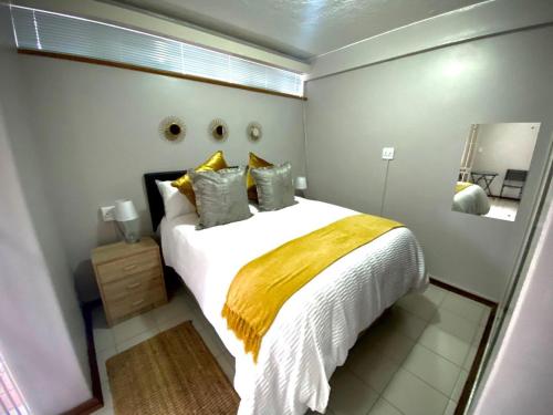 1 dormitorio con 1 cama grande con manta amarilla en Laboria 102 & 103, en Harrismith