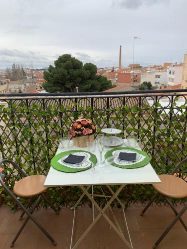a table with plates and glasses on a balcony at Atico bellasvistas en el centro Tomelloso Hoster Verona in Tomelloso