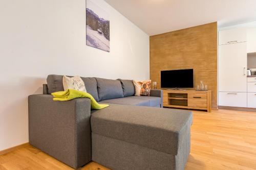 a living room with a gray couch and a television at Apart Blasblei in Sankt Gallenkirch