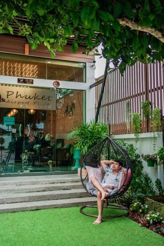 a man sitting in a swing in front of a store at Phuket Airport Place in Nai Yang Beach