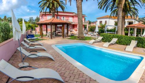 a pool with lounge chairs and a house at Hotel Villa Rosa in Porto Azzurro