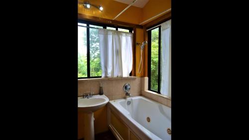 ein Bad mit einer Badewanne, einem Waschbecken und einem Fenster in der Unterkunft Sanpopo Tree Top Cottage - A Gold Standard Tourism Approved Vacation Home in San Ignacio