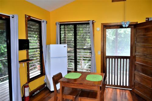 eine Küche mit einem Tisch und einem weißen Kühlschrank in der Unterkunft Sanpopo Tree Top Cottage - A Gold Standard Tourism Approved Vacation Home in San Ignacio
