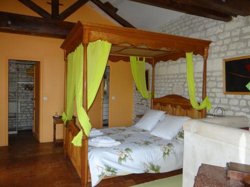 1 dormitorio con cama con dosel y cortinas amarillas en gîte du manoir des roches, en Saires