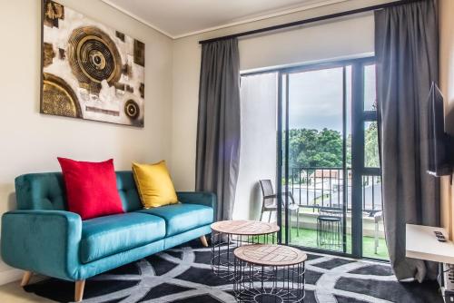 a living room with a blue couch and a balcony at Insaka's The Reid Apartment - Sandton in Sandown