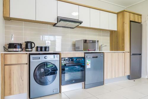 a kitchen with a washing machine and a washer at Insaka's The Reid Apartment - Sandton in Sandown