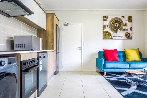 a living room with a blue couch in a kitchen at Insaka's The Reid Apartment - Sandton in Sandown
