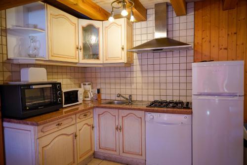 La cuisine est équipée d'un réfrigérateur blanc et d'un four micro-ondes. dans l'établissement la bergerie, à Mialanes