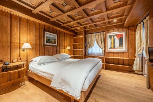 1 dormitorio con 1 cama grande en una habitación con paredes de madera en Parc Hotel Victoria, en Cortina dʼAmpezzo