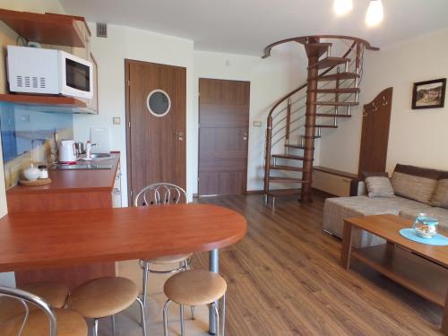 a kitchen and a living room with a table and a spiral staircase at Willa Laura Rowy - Apartamenty nad morzem in Rowy