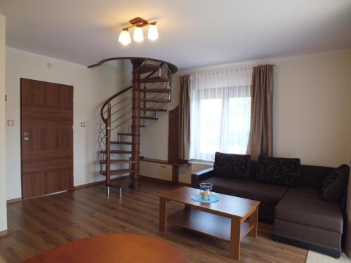 a living room with a spiral staircase and a couch at Willa Laura Rowy - Apartamenty nad morzem in Rowy