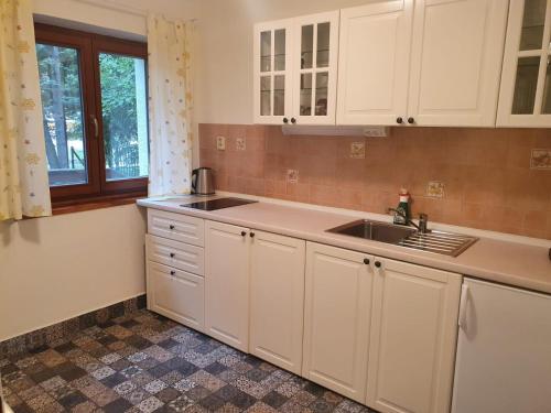 a kitchen with white cabinets and a sink and a window at Zelený dom in Modra