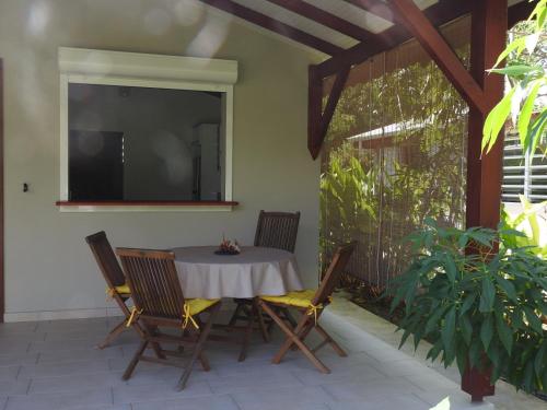 a table with chairs and a television on a patio at Kreyol Eden Cottage in Le Gosier