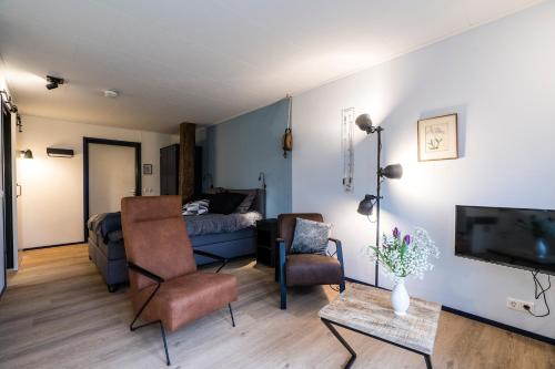 a living room with a bed and a couch and a tv at B&B De Oldambtster in Beerta