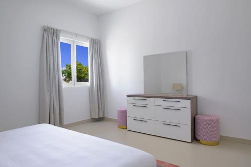 a bedroom with a bed and a dresser and a window at Le Sifah - Golf Lake Apartments in As Sīfah