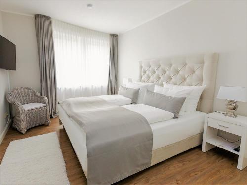 a white bedroom with a large bed and a window at Techts Strandhaus in Timmendorfer Strand