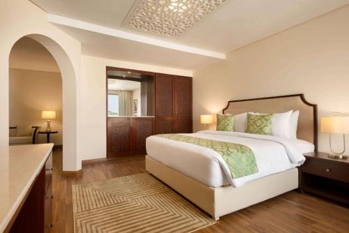 a bedroom with a large bed and a bathroom at Ramada by Wyndham Lahore Gulberg II in Lahore
