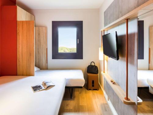 a hotel room with two beds and a tv at ibis budget Stein Maastricht in Stein