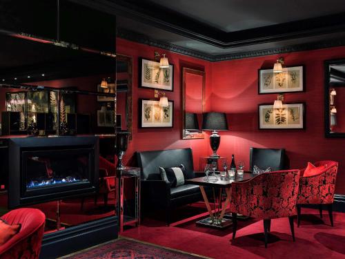 a red room with a table and chairs and a fireplace at Sofitel Queenstown Hotel & Spa in Queenstown