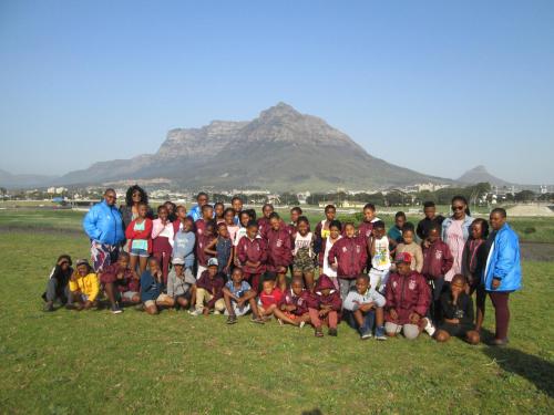 a group of people posing for a picture with mountains in the background at Lighthouse Farm Backpackers Lodge in Cape Town