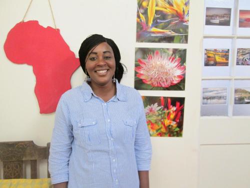 a woman standing in front of a wall with paintings at Lighthouse Farm Backpackers Lodge in Cape Town