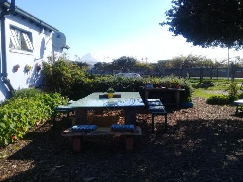 a picnic table with two chairs in a yard at Lighthouse Farm Backpackers Lodge in Cape Town