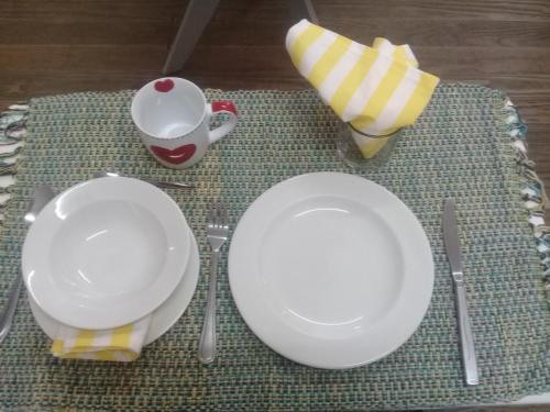 a table with white plates and utensils and a cup at Lighthouse Farm Backpackers Lodge in Cape Town