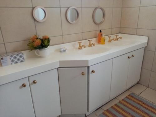baño con lavabo blanco y 2 espejos en Lighthouse Farm Backpackers Lodge, en Ciudad del Cabo