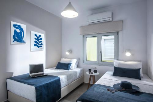 una habitación con 2 camas y un ordenador portátil en una mesa en Aether by Nymphs residence I, en Kokkinos Pirgos