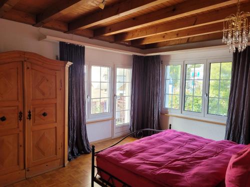 a bedroom with a large purple bed in a room with windows at Villa Castagna Guesthouse in Lucerne