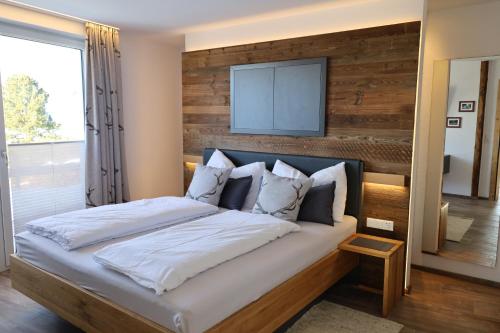 a bedroom with a large bed with a wooden wall at Gschwendtalm Tirol - Luxus-Apartment für Ihre Auszeit in Tulfes