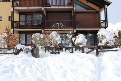 a house with snow in front of it at Studio Residence Le Stella in Ancelle