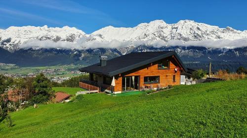 a house on a hill with mountains in the background at Gschwendtalm Tirol - Luxus-Apartment für Ihre Auszeit in Tulfes
