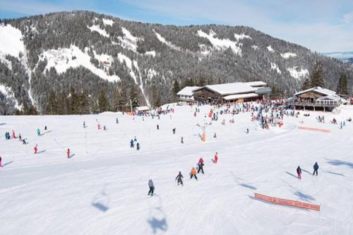 a group of people skiing down a snow covered slope at Le Relai S34 - Grand et lumineux studio avec coin montagne 4-6 pers avec WIFI, 50m des pistes, grand balcon exposé SUD, DRAPS NON COMPRIS in Saint-Jean-dʼAulps