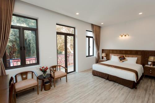 a bedroom with a bed and two chairs and windows at Korea Hotel Bac Giang in Làng Thành