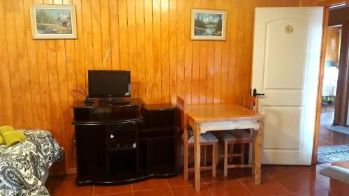 a room with a table and a desk with a television at Apart Hotel Arrayán in Coihaique