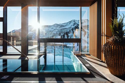 a house with a pool and a view of a mountain at Hotel Alpenstern in Damuls